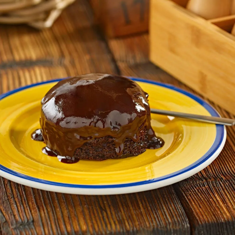 Warm chocolate pudding with glossy sauce on a golden plate